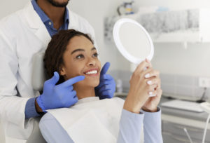 woman smiling looking at her dental results in the mirror