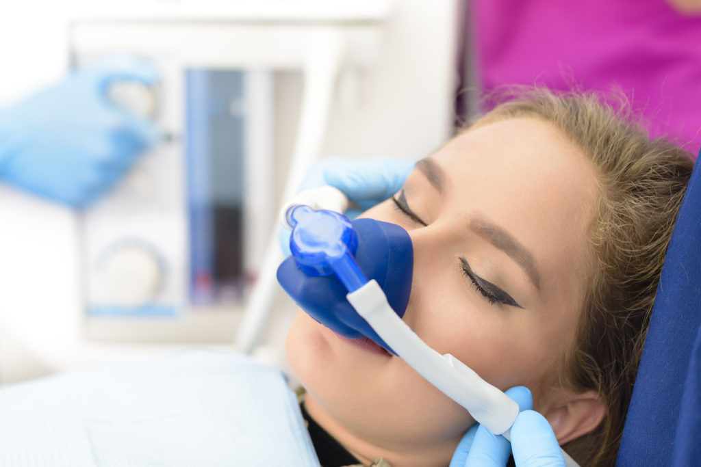 Close up of woman's face receiving nitrous gas before sedation dentistry