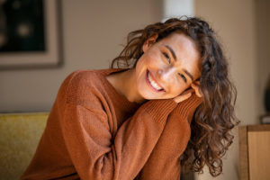 Portrait of comfortable woman in winter clothes relaxing on armchair.