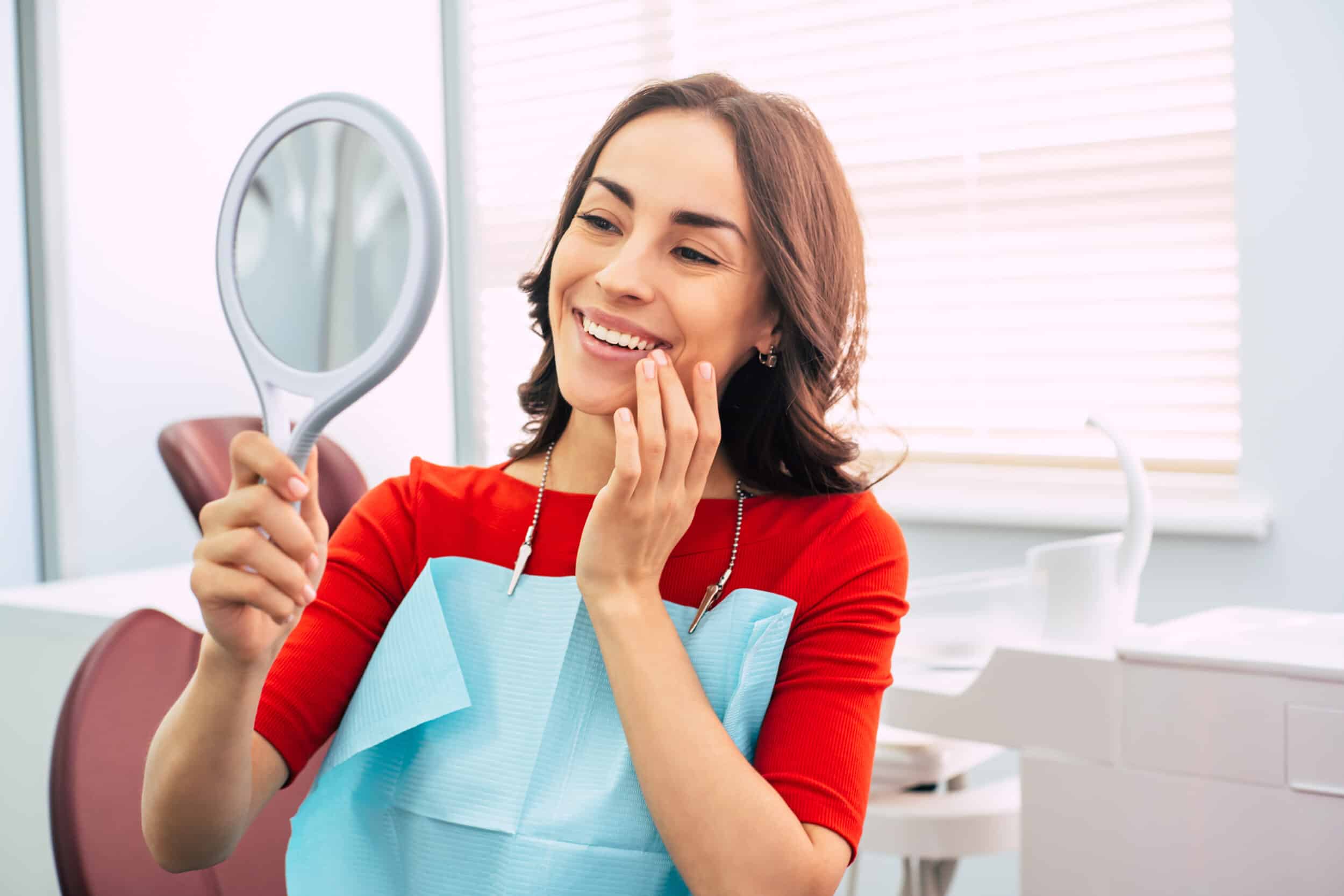 A woman looking in the mirror after Fotona Laser Dentistry treatments in Melville, NY