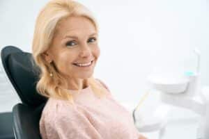 A woman sitting in a dentist's chair and smiling after getting 3D facial scanning