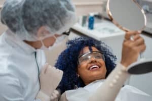 A woman looking in the mirror after a restorative dentistry appointment