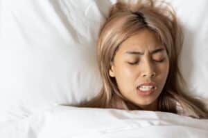 A woman lying in bed and grinding her teeth before getting BOTOX® for bruxism