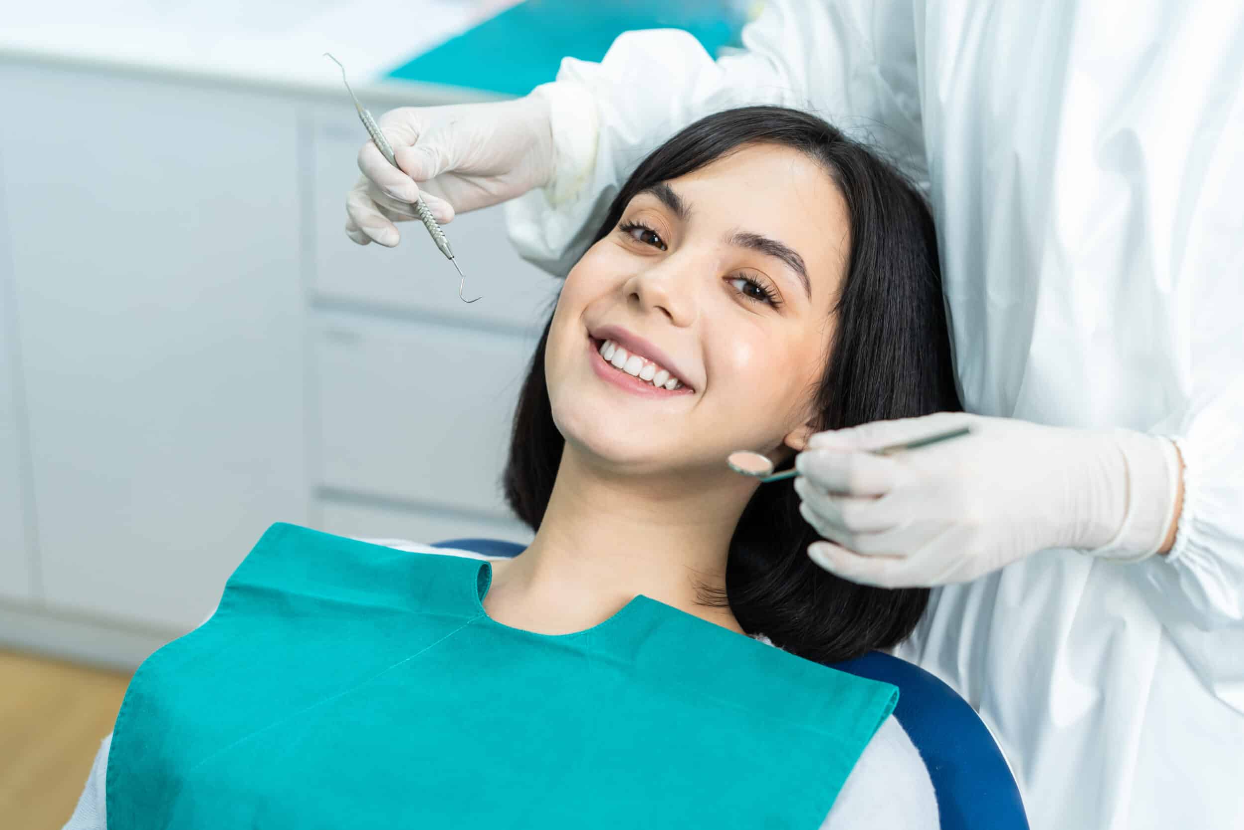 A woman smiling in a dentist's chair during an endodontic procedure
